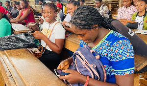 Un candidat consulte son téléphone devant un centre de concours militaire au Cameroun