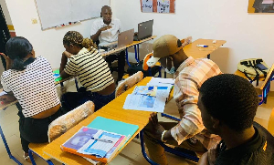 Des joueurs composent des mots en langue Douala sur le plateau du jeu Elomban.